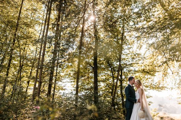 Romantisches Brautpaar im Sonnenlicht des Waldes
