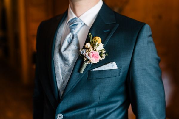 Bräutigam mit Ansteckblume bei der Hochzeit auf der Gutsalm Harlachberg