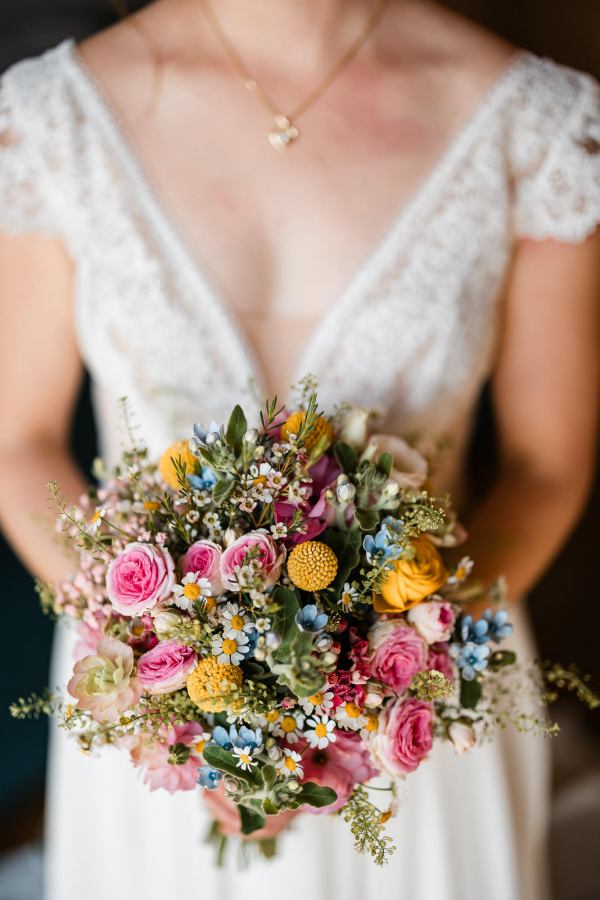 Braut mit buntem Brautstrauß bei der Hochzeit auf der Gutsalm Harlachberg