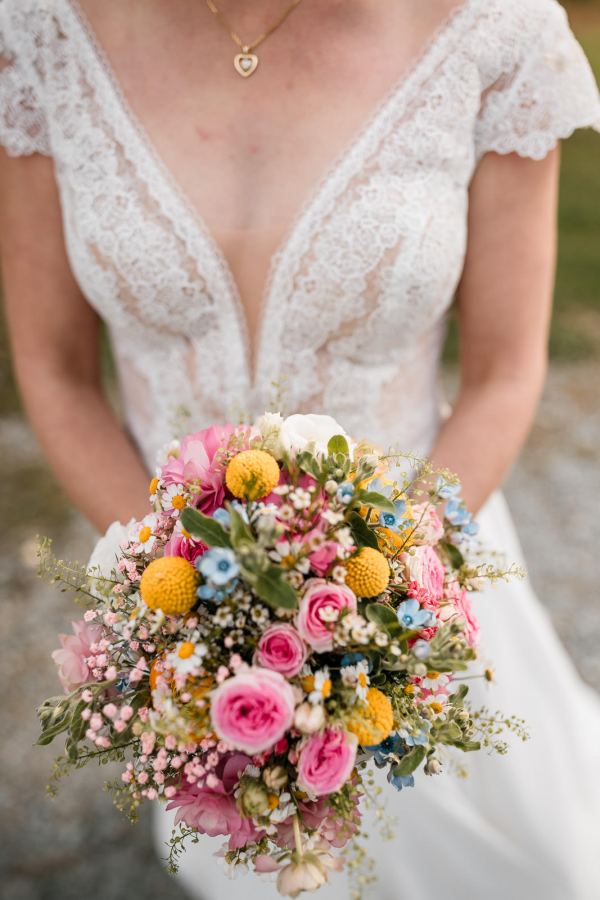 Braut mit farbenfrohem Brautstrauß bei der Hochzeit auf der Gutsalm Harlachberg